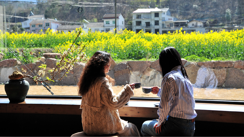People enjoy coffee amid blossoming rapeseed flowers in Yichang